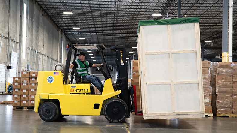 Forklift loading pallets of cardboard boxes for shipment